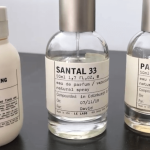 ル ラボ サンタル33香水瓶の画像。50ml サンタル33 オードパルファム スプレー瓶が中央に配置され、エディンバラで調香された'David'名義のカスタムメイド香水であることがラベルに表示されている。透明ガラス瓶にミニマルなタイポグラフィーが施され、左右には他のル ラボ製品も並んでいる。